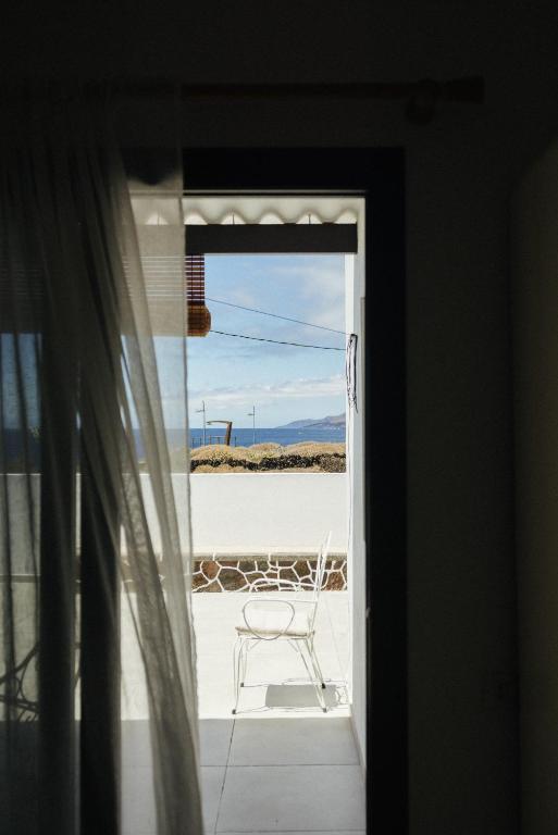 a chair sitting on a porch looking out a window at La Casa de La Caleta by Taller96 - El Hierro Island - in La Caleta