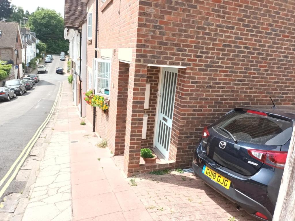 een auto geparkeerd aan de zijkant van een bakstenen gebouw bij Chez Jo Apartments in Lewes