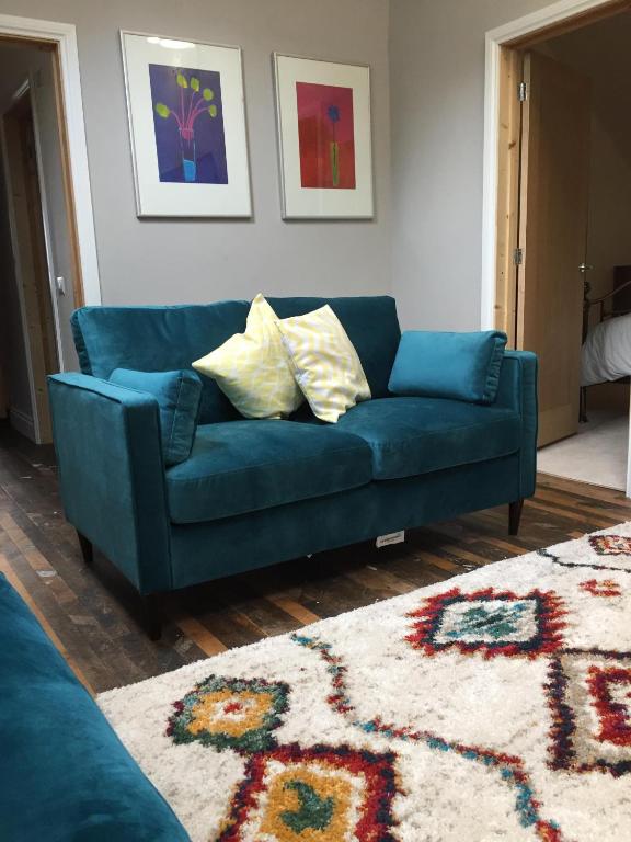 a blue couch in a living room with a rug at Lime Tree Cottage in Tillingham