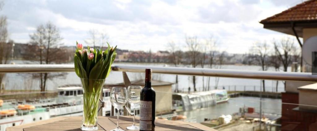 una botella de vino y un jarrón con flores en una mesa en Willa Port Rezydencje, en Ostróda