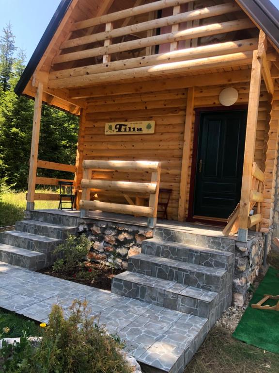 eine Blockhütte mit einer Treppe, die zu einer Tür führt in der Unterkunft Tilia Cottage Banjska stena in Mitrovac
