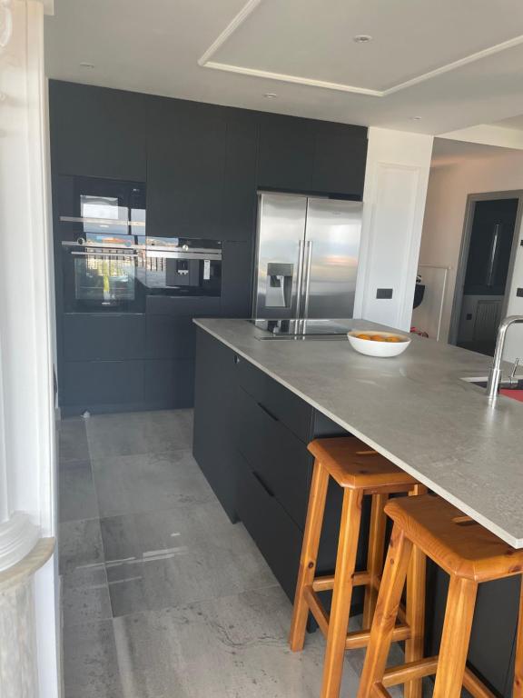 a kitchen with black cabinets and a counter with stools at Kornelijas House in Santa Susanna