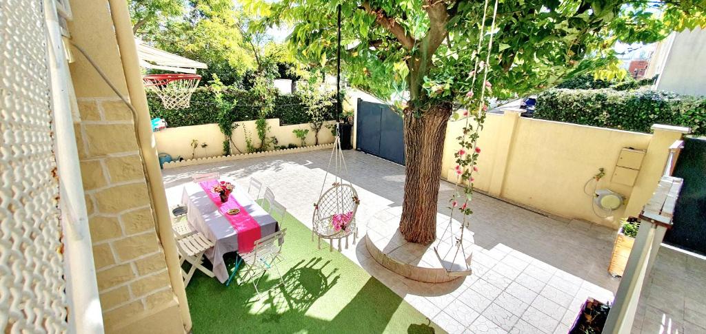 Elle offre une vue sur la terrasse dotée d'une table et d'un arbre. dans l'établissement MAISON APPARTEMENT TOUT CONFORT À 10mn des plages, à Montpellier