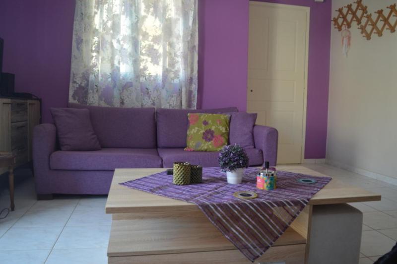 uma sala de estar com um sofá roxo e uma mesa em Mauve Apartment em Argostólion