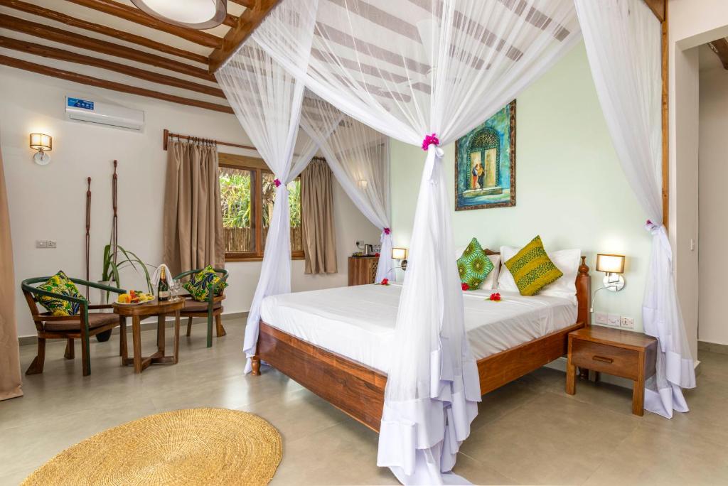 a bedroom with a bed with a mosquito net at Zanzibar Queen Hotel in Matemwe