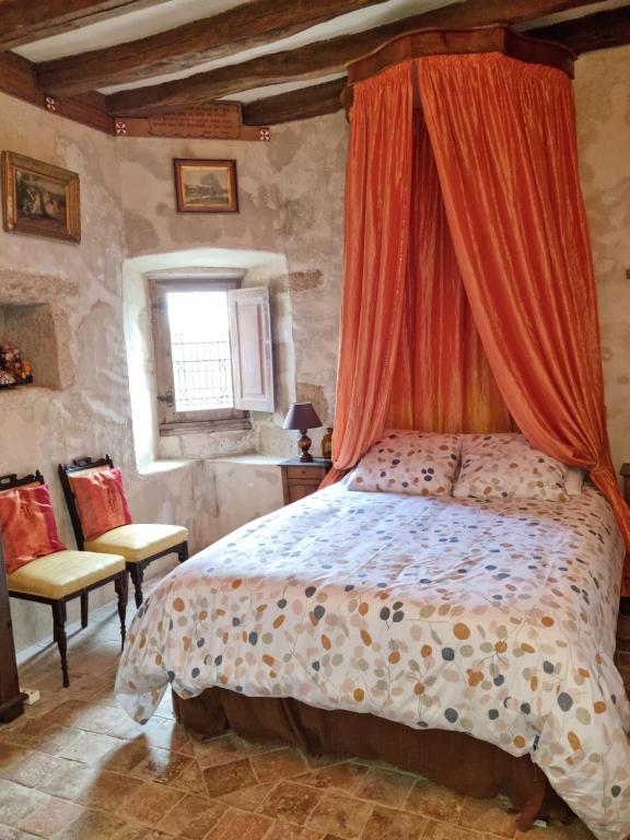 a bedroom with a bed with an orange canopy at Château de la Cressonnière in Antigny