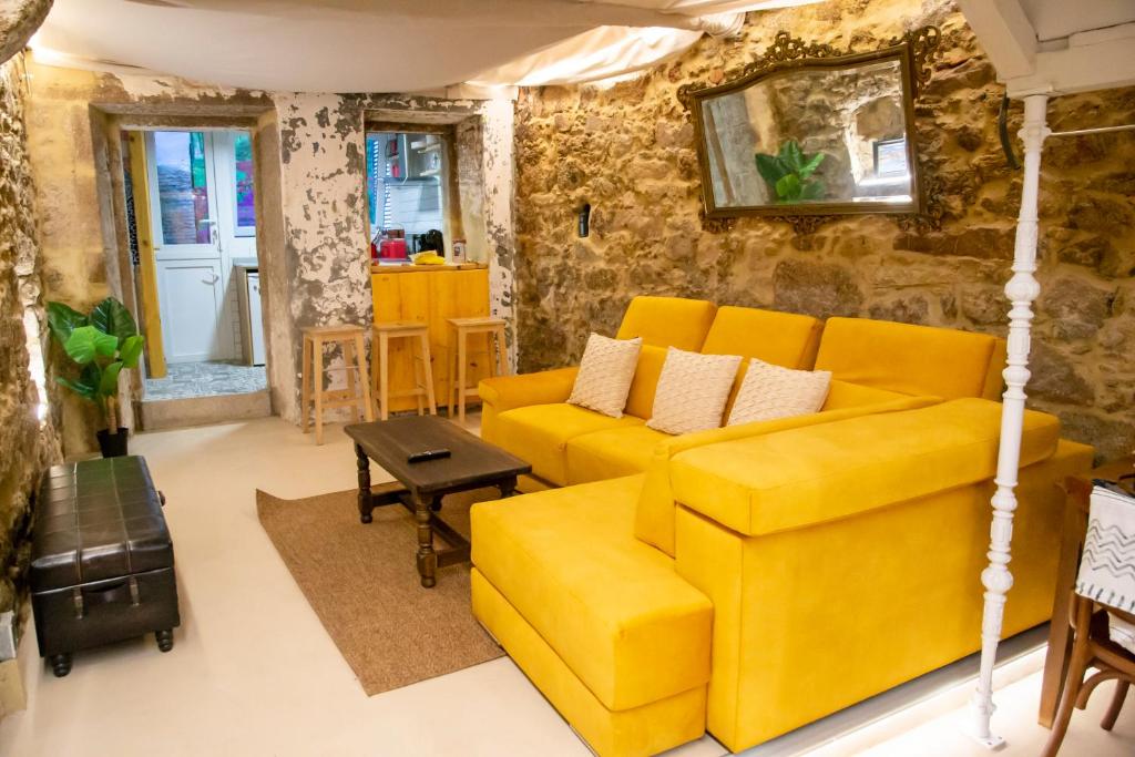 ein Wohnzimmer mit einem gelben Sofa und einem Tisch in der Unterkunft Apartamento Ciudad Vieja Coruña in A Coruña