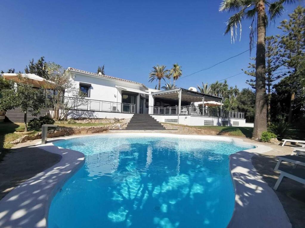 a large swimming pool in front of a house at Villa Dune, Luxury Villa, 5 min walk to the beach in Marbella