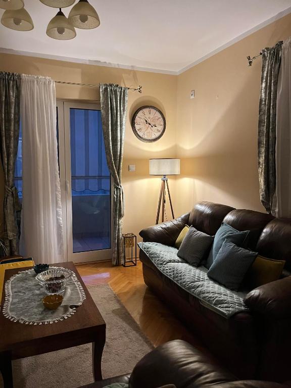 a living room with a couch and a clock on the wall at Apartman Nina in Kotor