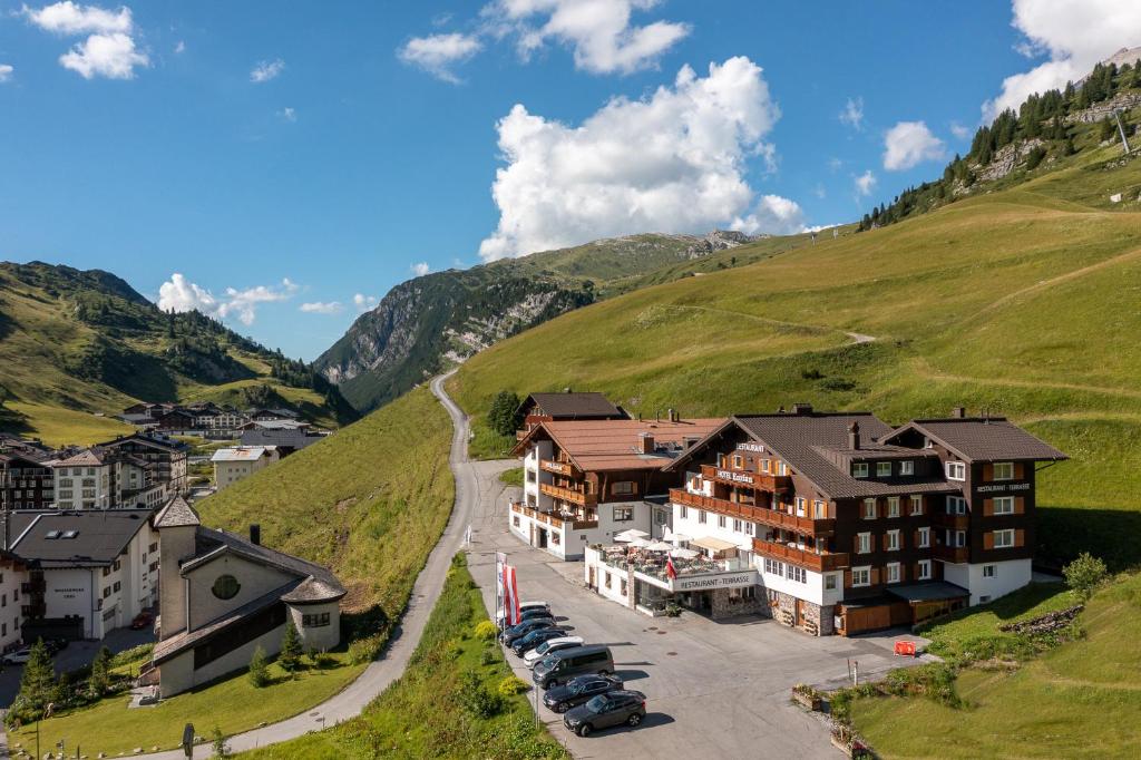 ein Dorf in den Bergen mit parkenden Autos in der Unterkunft Hotel Enzian in Zürs am Arlberg