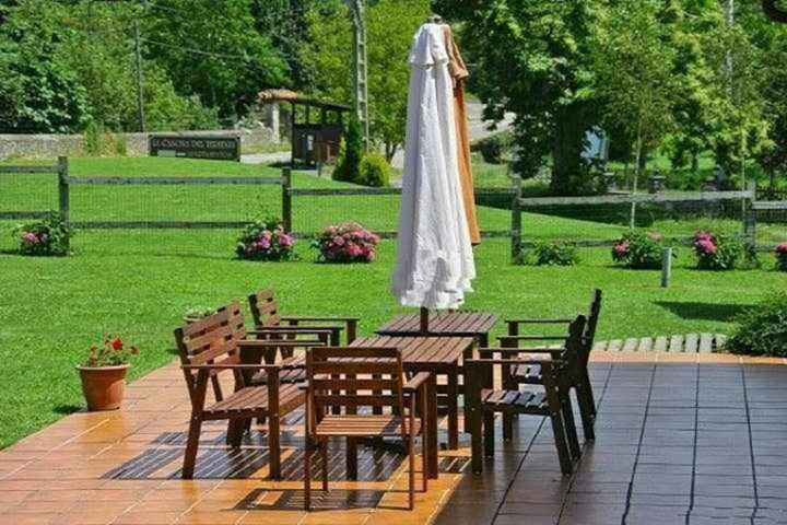 stół piknikowy z parasolem i krzesłami oraz park w obiekcie Apartamento familiar cercano a playa de Rodiles 7 w mieście El Olivar