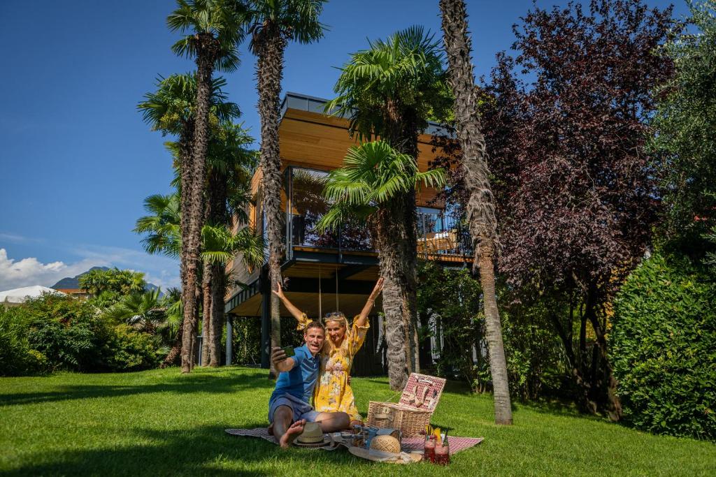 two children sitting on the grass in front of a house at TreeLodgy, The Tree House in Riva del Garda