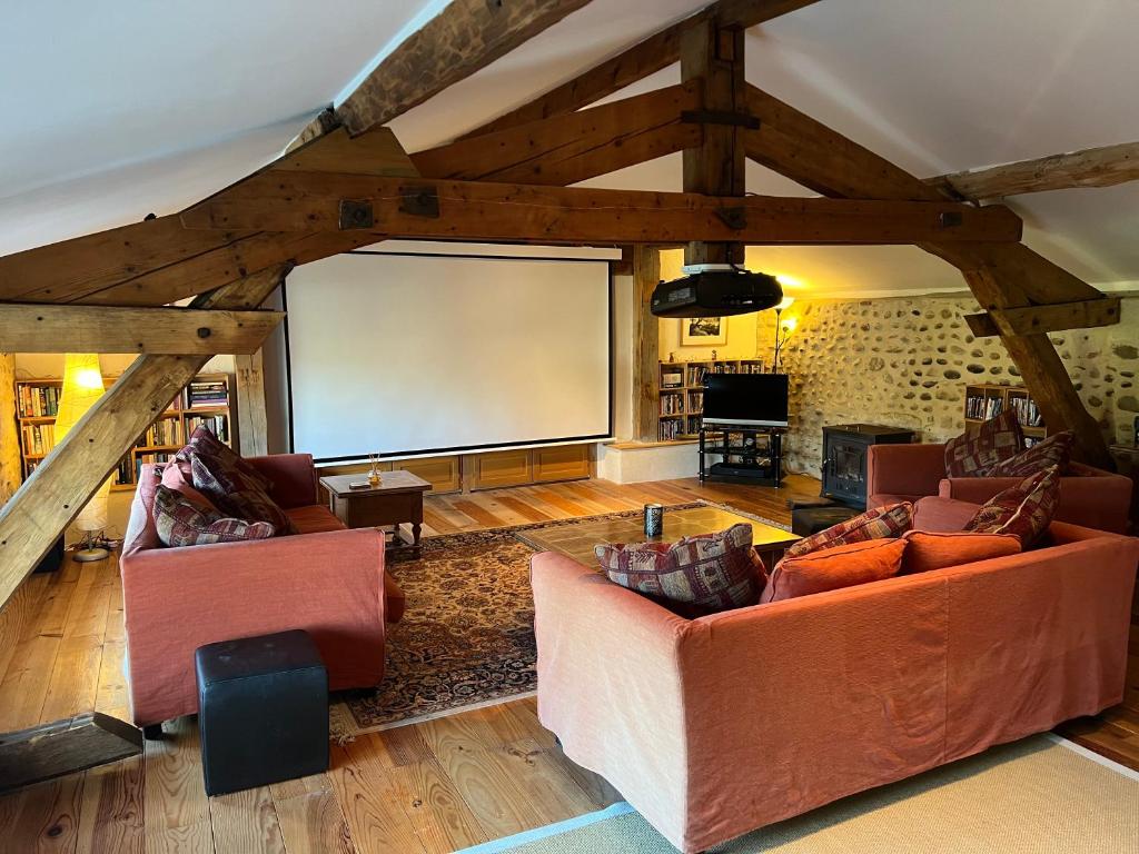 una sala de estar con 2 sofás y una pantalla grande en La Joie de Vivre en Bonnefont