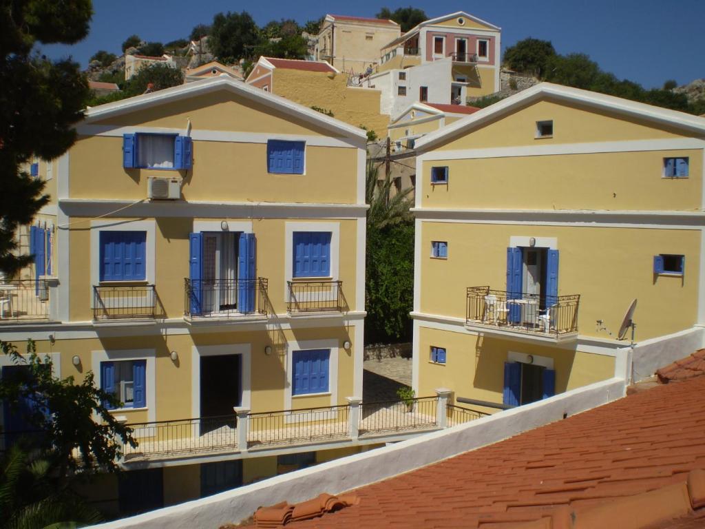 rząd żółtych domów z niebieskimi okiennicami w obiekcie Anastasia Hotel w mieście Simi