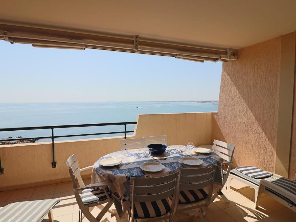 une table et des chaises sur un balcon avec vue sur l'océan dans l'établissement Appartement Climatisé Front de Mer avec Terrasse, Piscine, et Garage Privatif à Sète - FR-1-472A-217, à Sète
