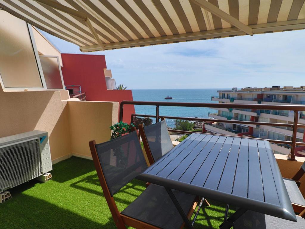 une table et des chaises sur un balcon avec vue sur l'océan dans l'établissement Superbe 2P cabine climatisé, terrasse, piscine, Wi-Fi, parking - FR-1-472A-238, à Sète