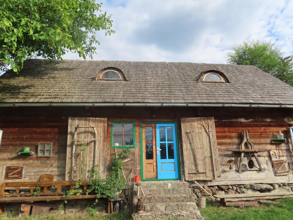 an old log cabin with a blue door at Babou Maramures in Breb