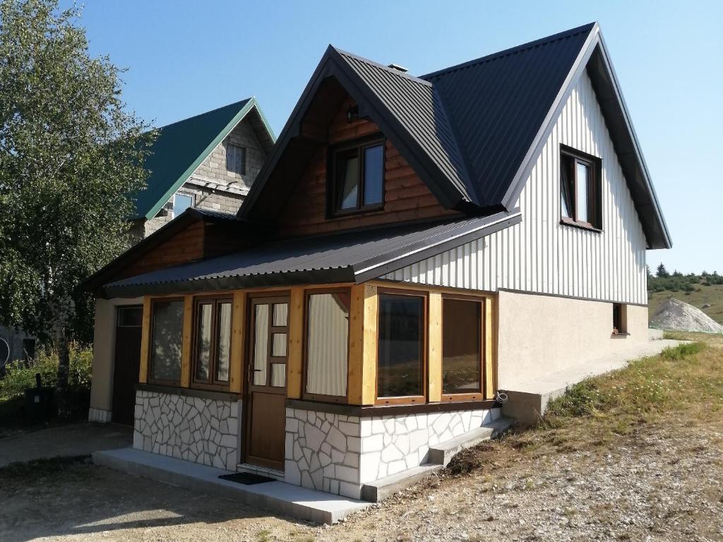 uma pequena casa com um telhado preto em Bungalows and rooms Ivan em Žabljak