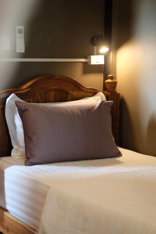 a bed with a wooden headboard and a white pillow at Bloom Cafe & Hostel in Ko Lipe
