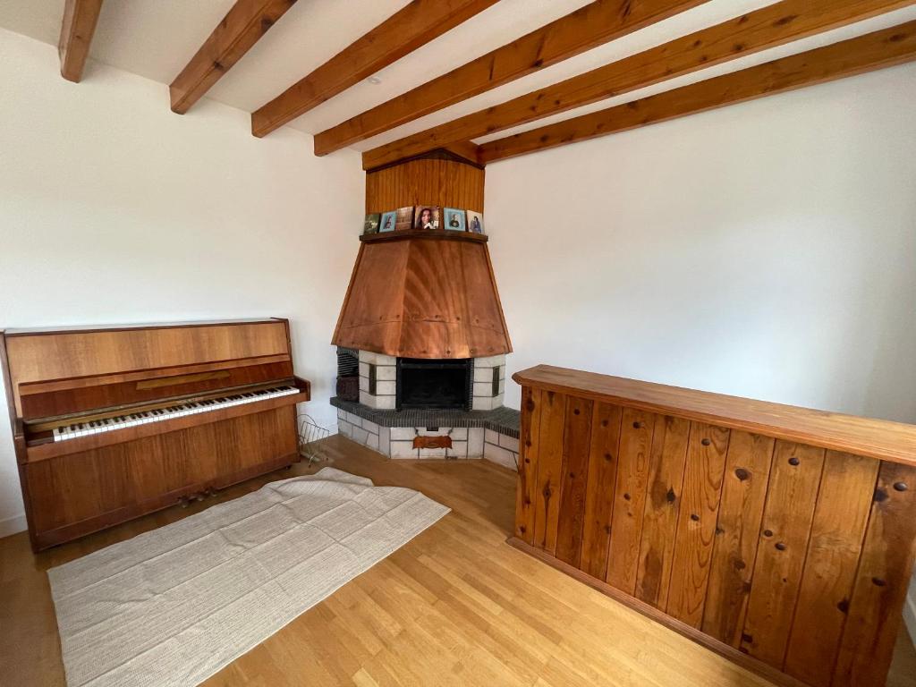 an empty room with a fireplace and a piano at Appartement dans maison avec cour et parc in Fresnes-en-Woëvre