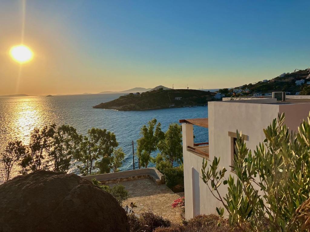 a house with the sun setting over the water at Litois Houses Patmos in Sapsila
