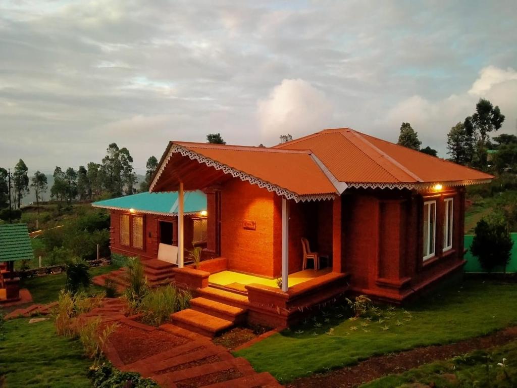 a small house with an orange roof at Holygram Krushi Paryatan in Panchgani