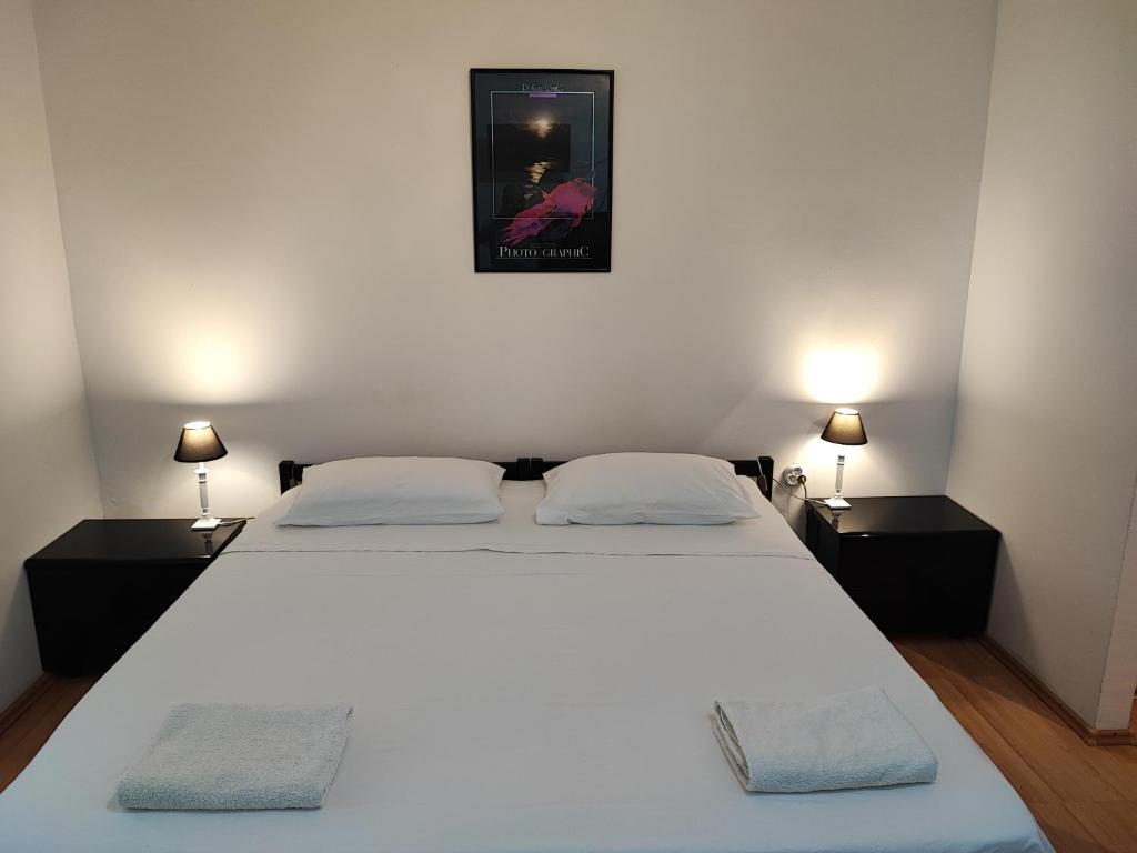 1 dormitorio con 1 cama blanca grande y 2 mesitas de noche en Private Accommodation Raspudic, en Split