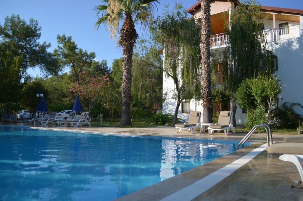 a swimming pool with chairs and palm trees at Farmside OTEL in Fethiye
