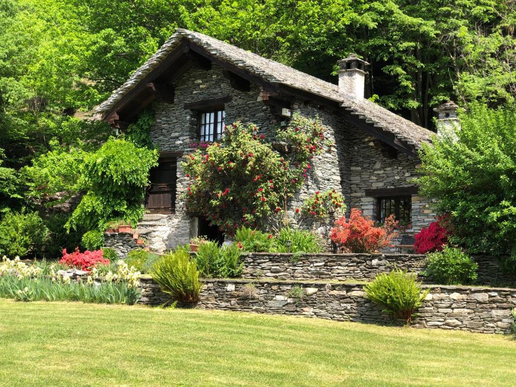 una casa in pietra con fiori di fronte a un cortile di Le Primule a Piedilago