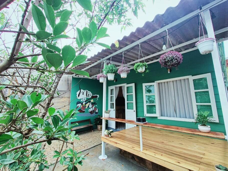 uma casa verde com um deque de madeira em frente em MOre Home - Ngôi nhà nghĩ dưỡng tại Đà Lạt em Da Lat
