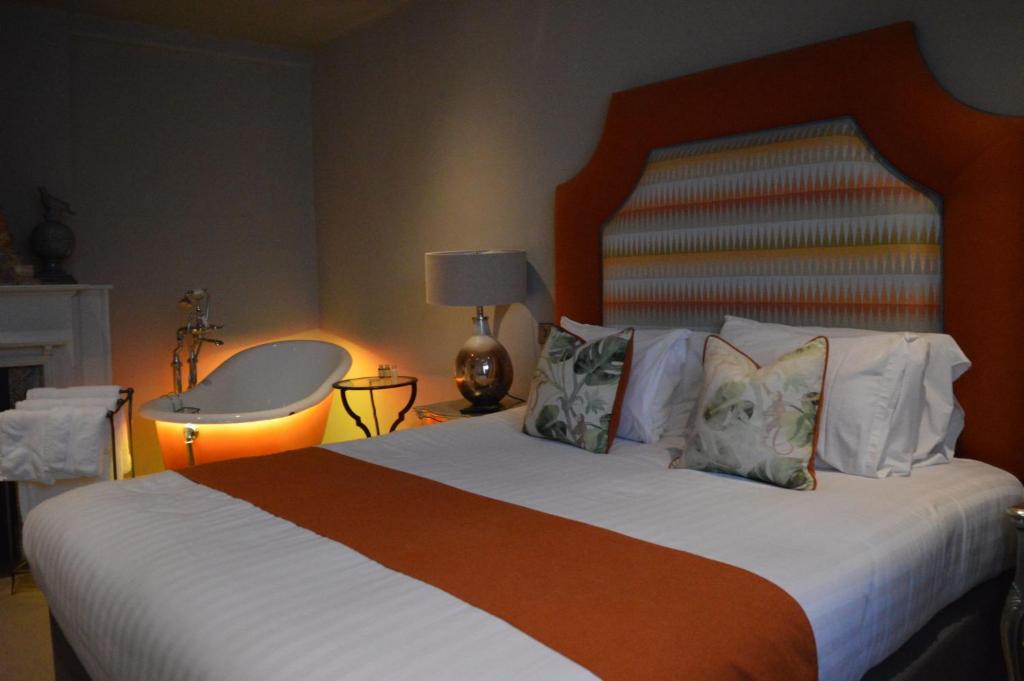 a bedroom with a large bed with white sheets and pillows at Long Melford Swan in Long Melford