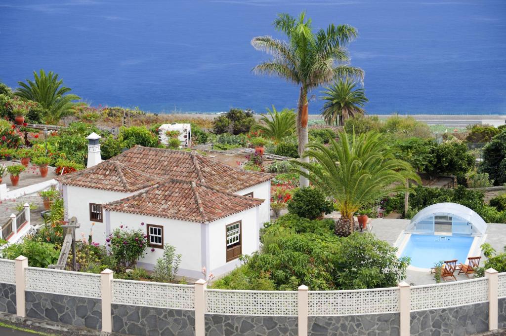 a white house with a pool and palm trees at Casa Rural Priscila in Mazo