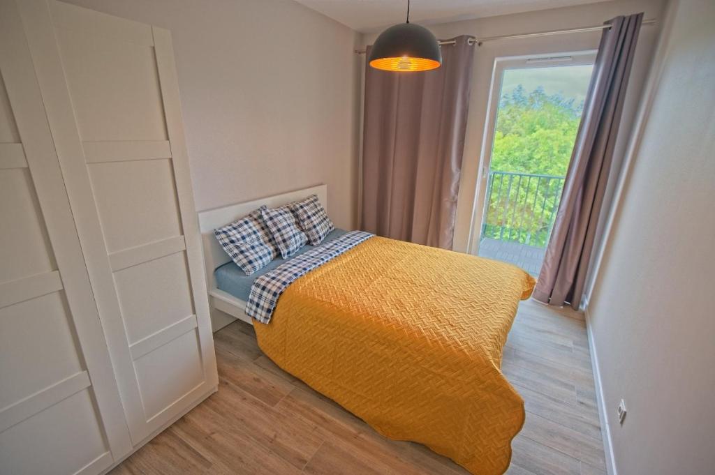 sypialnia z łóżkiem z żółtym kocem i oknem w obiekcie Apartamenty Poproszę na Plażę w Jastrzębiej Górze