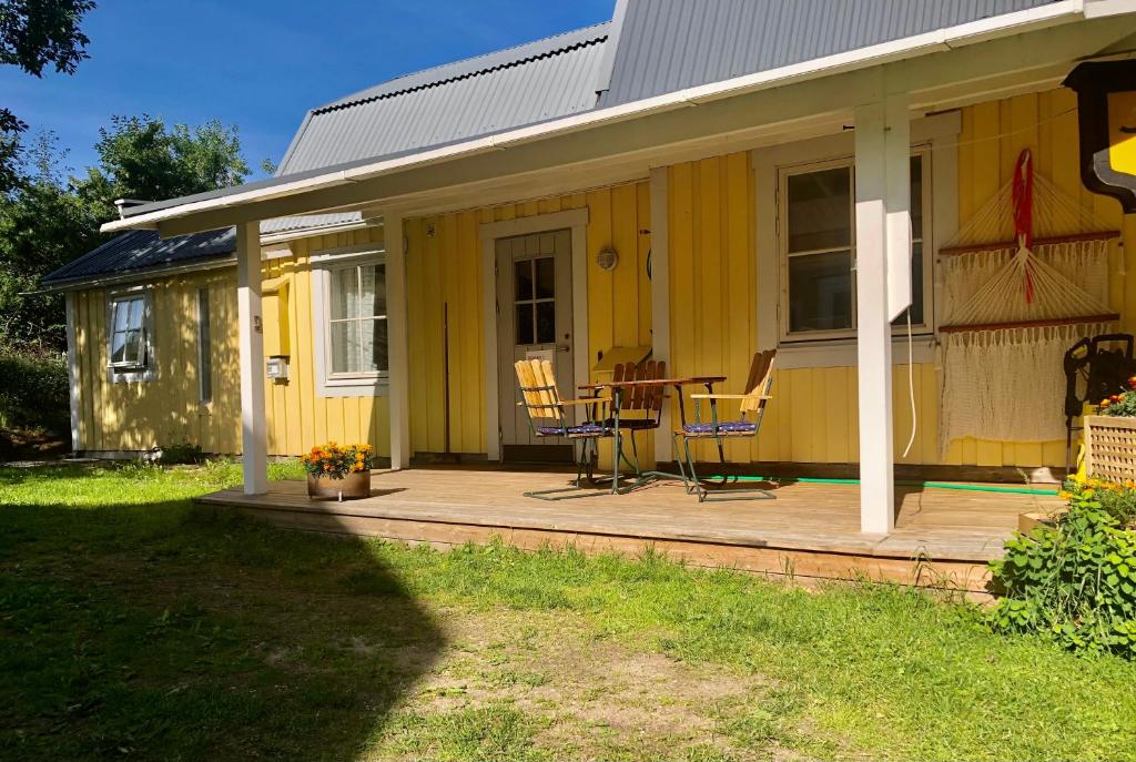 ein gelbes Haus mit einem Tisch und Stühlen auf einer Veranda in der Unterkunft Ögränd 2 - Nyrenoverad toppmodern lägenhet in Sveg