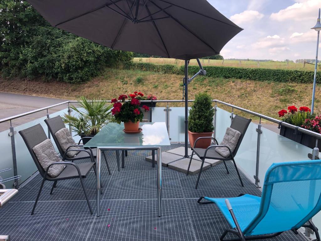Ferienwohnung Sonnenterrasse في Schlausenbach: فناء مع طاولة وكراسي ومظلة