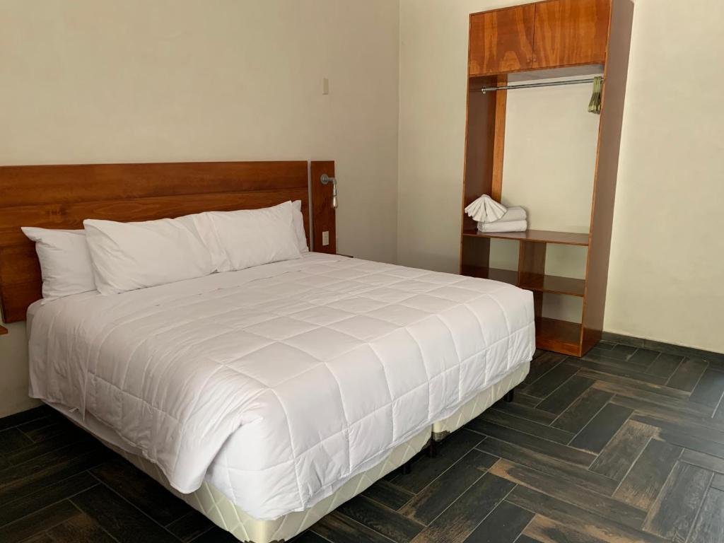 a bedroom with a white bed and a mirror at Los &Aacute;ngeles Hotel in Jalpan