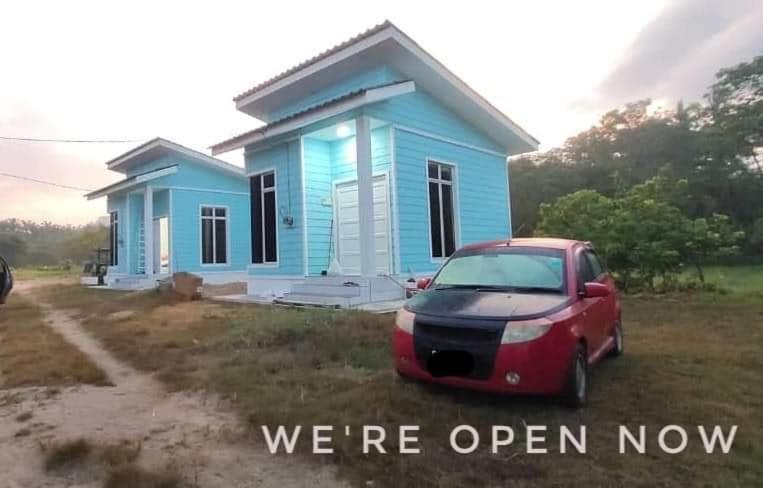 a blue house with a red car parked in front of it at Teratak Sherra Roomstay in Machang