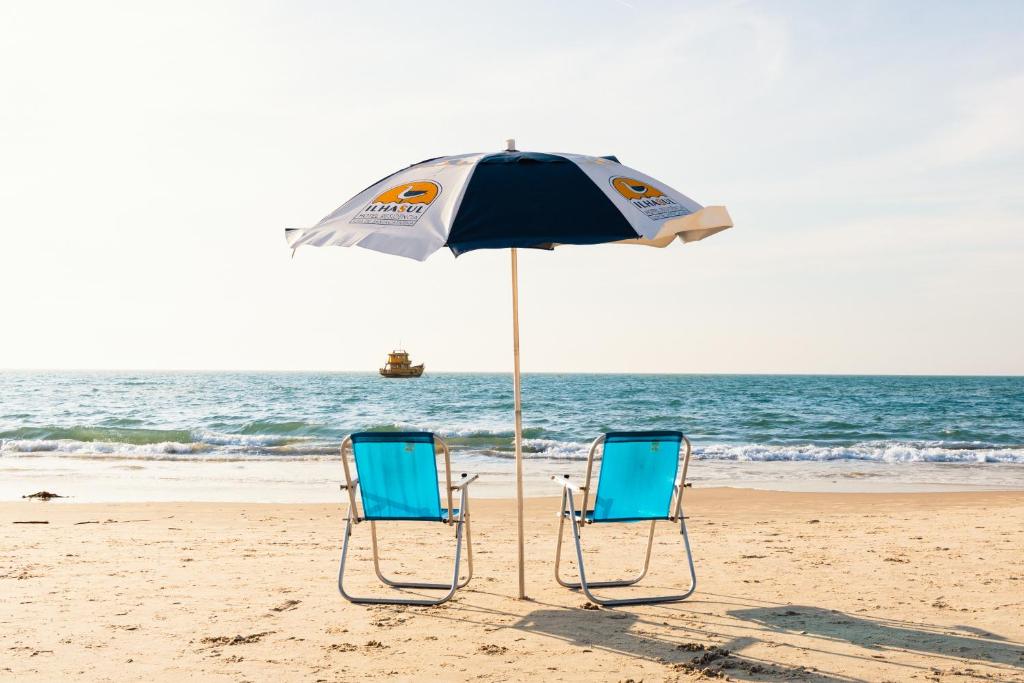 two chairs and an umbrella on the beach at Ilhasul Hotel Residencia in Florianópolis