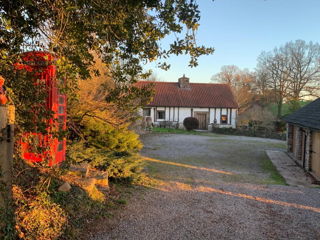 a house with a red fence in front of it at Medieval Cottage in rural Monmouthshire. in Raglan
