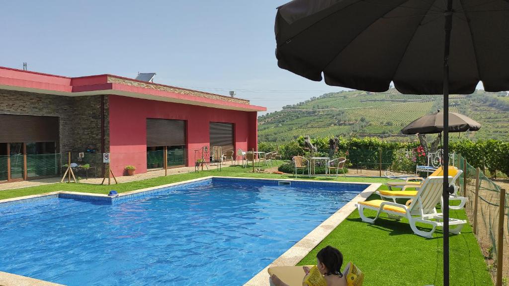 a woman sitting in a chair next to a swimming pool at Quinta dos Padrinhos - Suites in the Heart of the Douro in Lamego