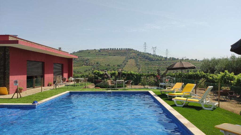 a swimming pool with chairs and a house at Quinta dos Padrinhos - Suites in the Heart of the Douro in Lamego