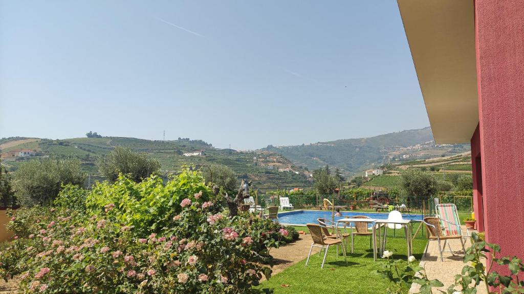 a garden with a table and chairs and a swimming pool at Quinta dos Padrinhos - Suites in the Heart of the Douro in Lamego