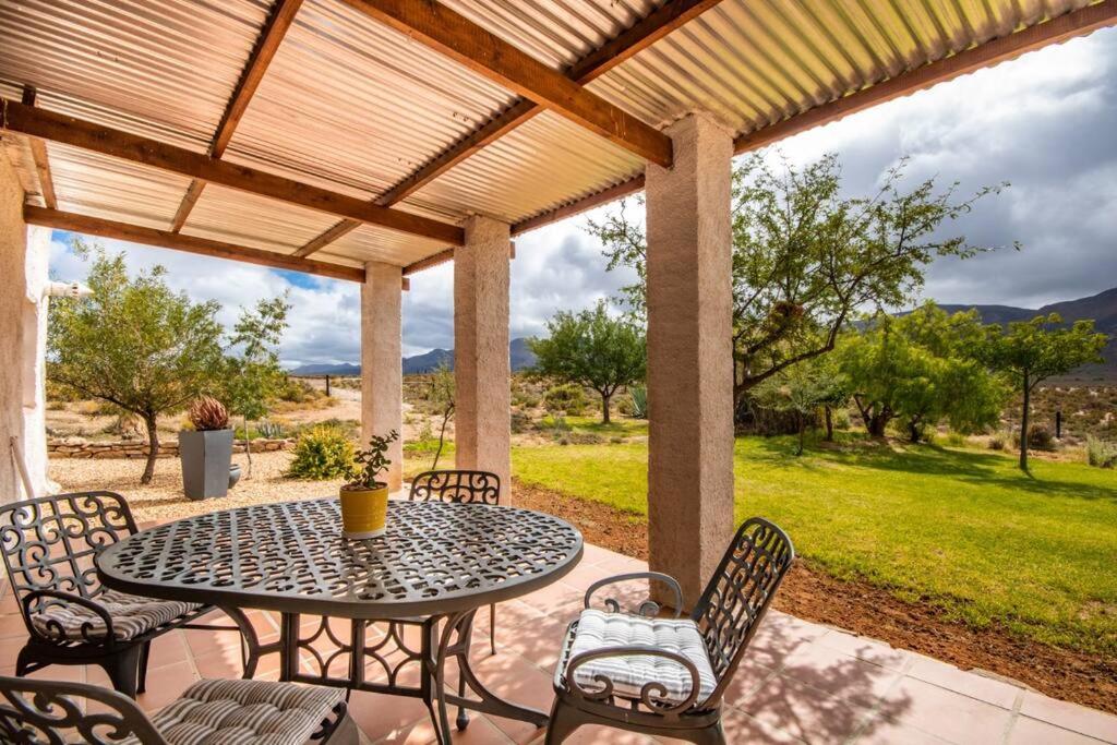 a patio with a table and chairs under a pergola at Tequila Sunrise Cottage at Karoofontein Guest Farm in Geelwal