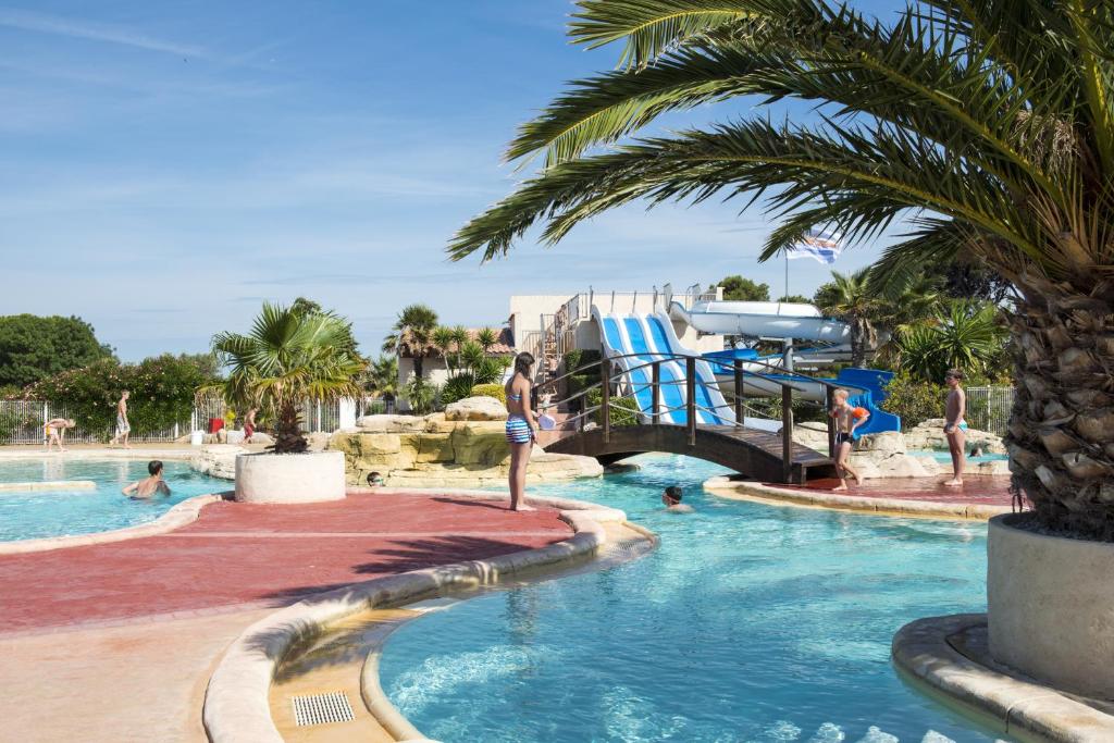 a man standing in a swimming pool at a resort at Domaine Les Mûriers in Vendres-Plage