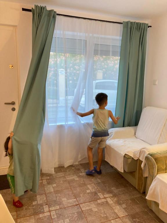 a little girl standing on a bed looking out of a window at LaNoi LaVoi in Mangalia