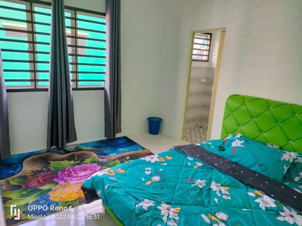 依斯干達的住宿－Raihan Homestay Seri Iskandar Perak Near UTP UITM，一间卧室配有一张带五颜六色棉被的床