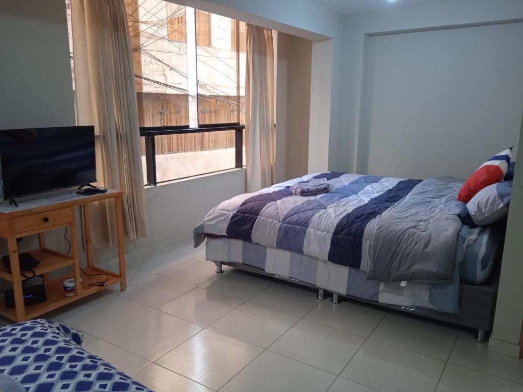 um quarto com uma cama, uma televisão e uma janela em La casa de Chepita em Cusco