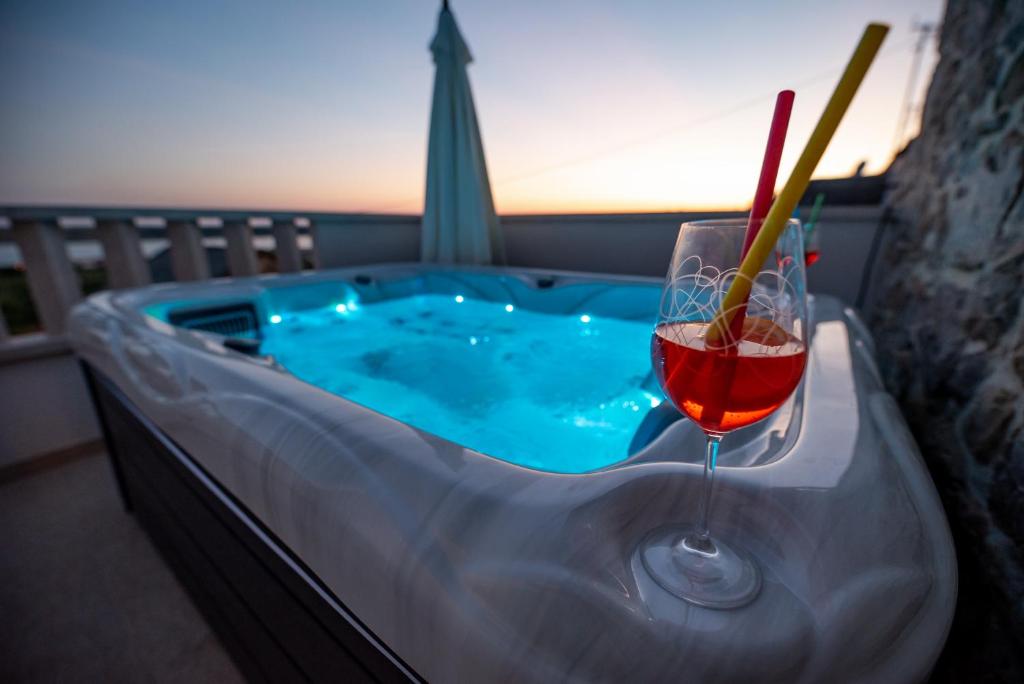 a hot tub with a glass of wine and a drink at Didov dvor in Ražanac