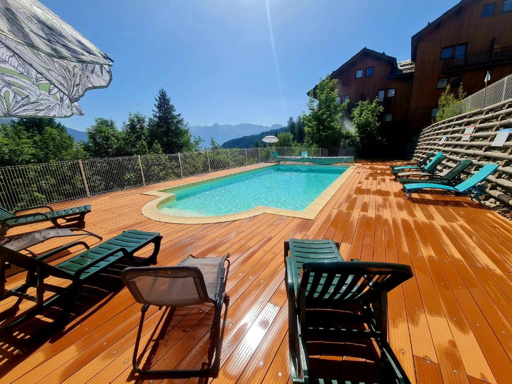 eine Terrasse mit Stühlen und einem Pool in der Unterkunft Appartement Puy Saint Vincent 4 personnes in Puy-Saint-Vincent