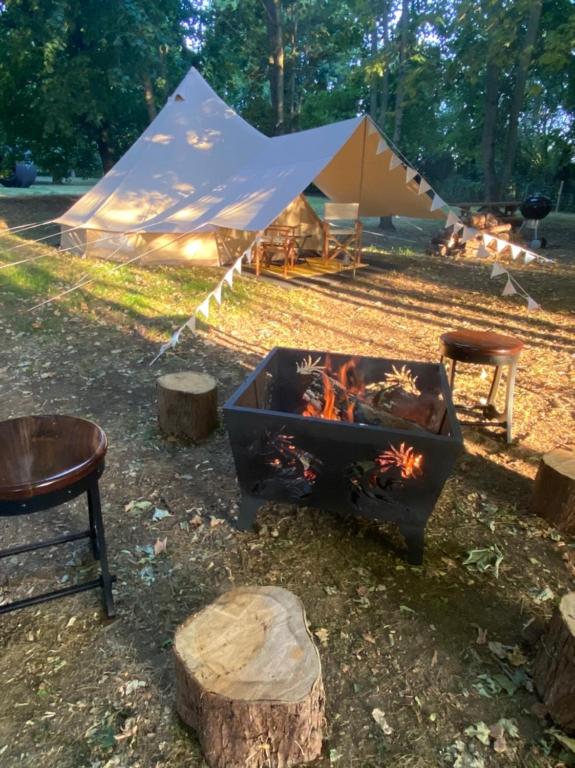 eine Feuerstelle mit einem Zelt im Hintergrund in der Unterkunft Eakley Manor Farm Glamping in Newport Pagnell